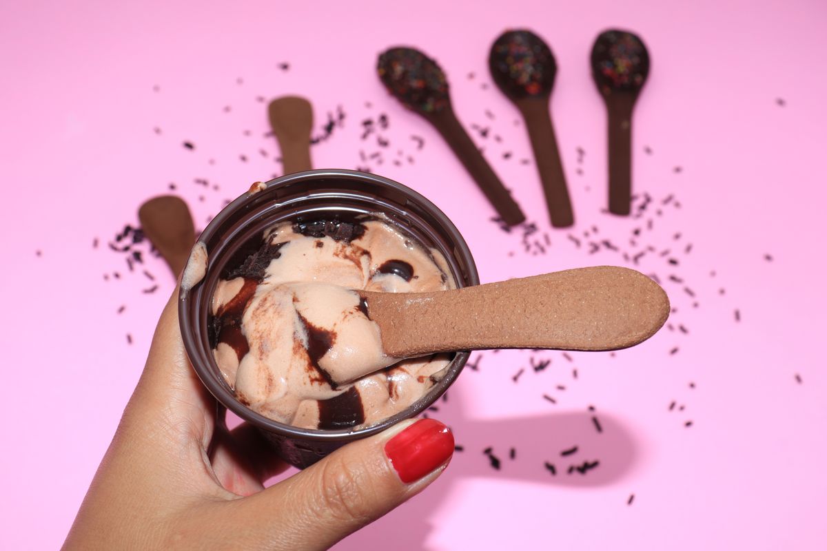 Chocolate ice cream cup with an edible chocolate cookie spoon on a pink background