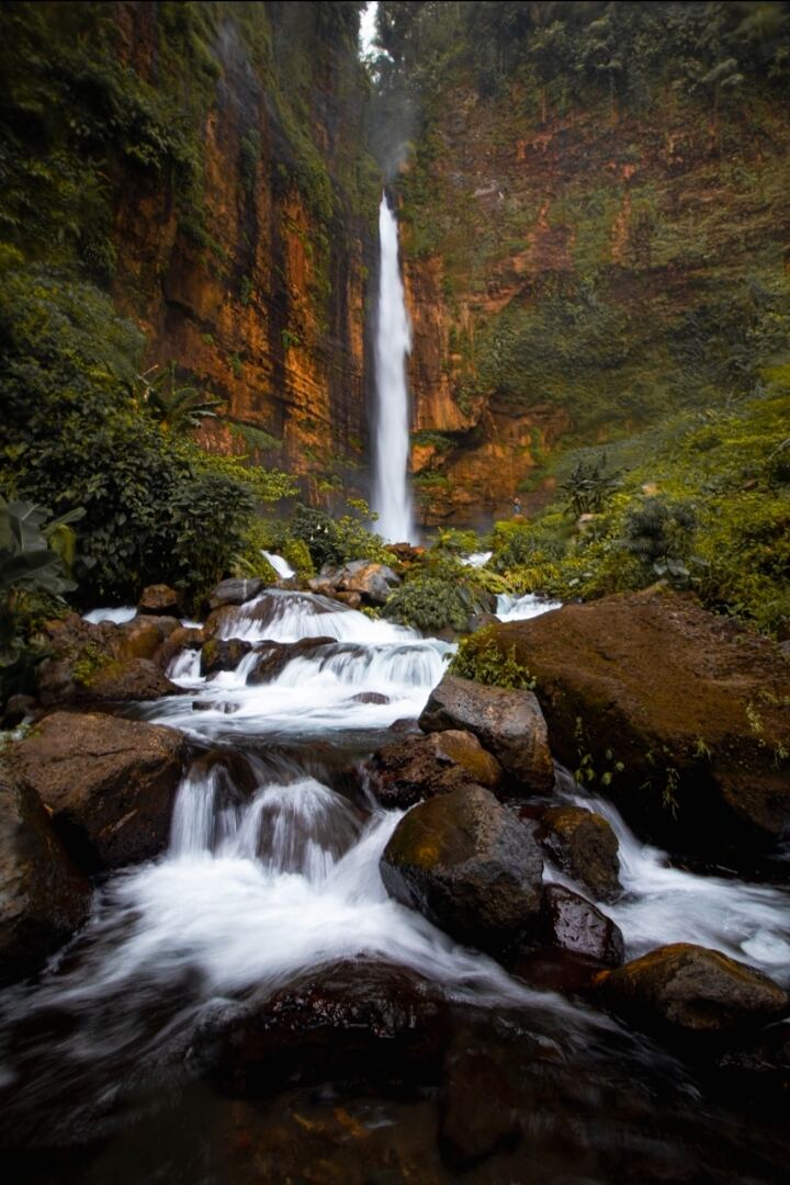 Tall waterfall in a rocky canyon flowing over boulders into a stream